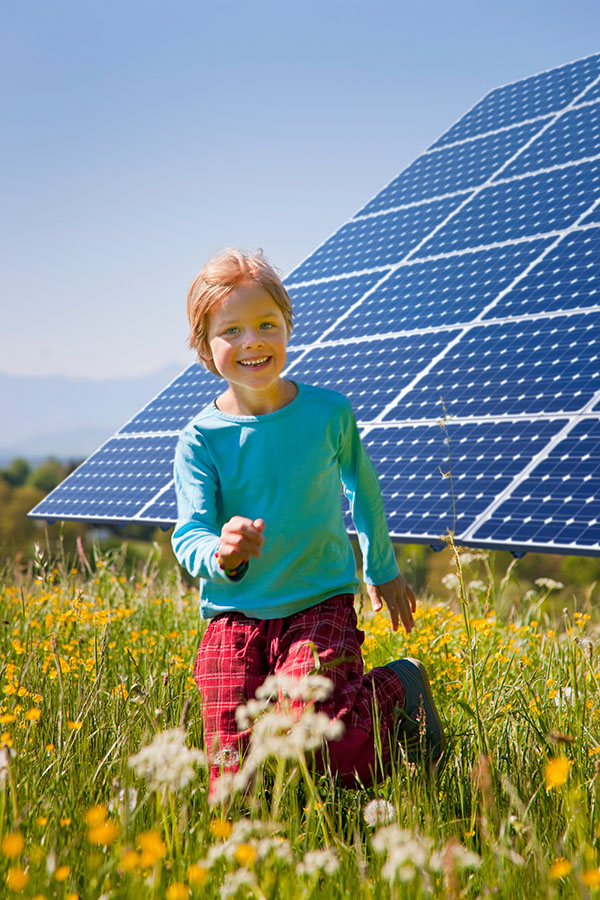 boy playing in field by solar panel